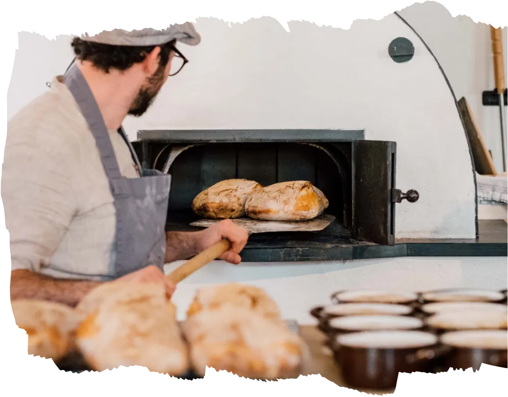 Seminarleiter Rudi Pichler nimmt das fertige Ciabatta aus dem Holzofen.